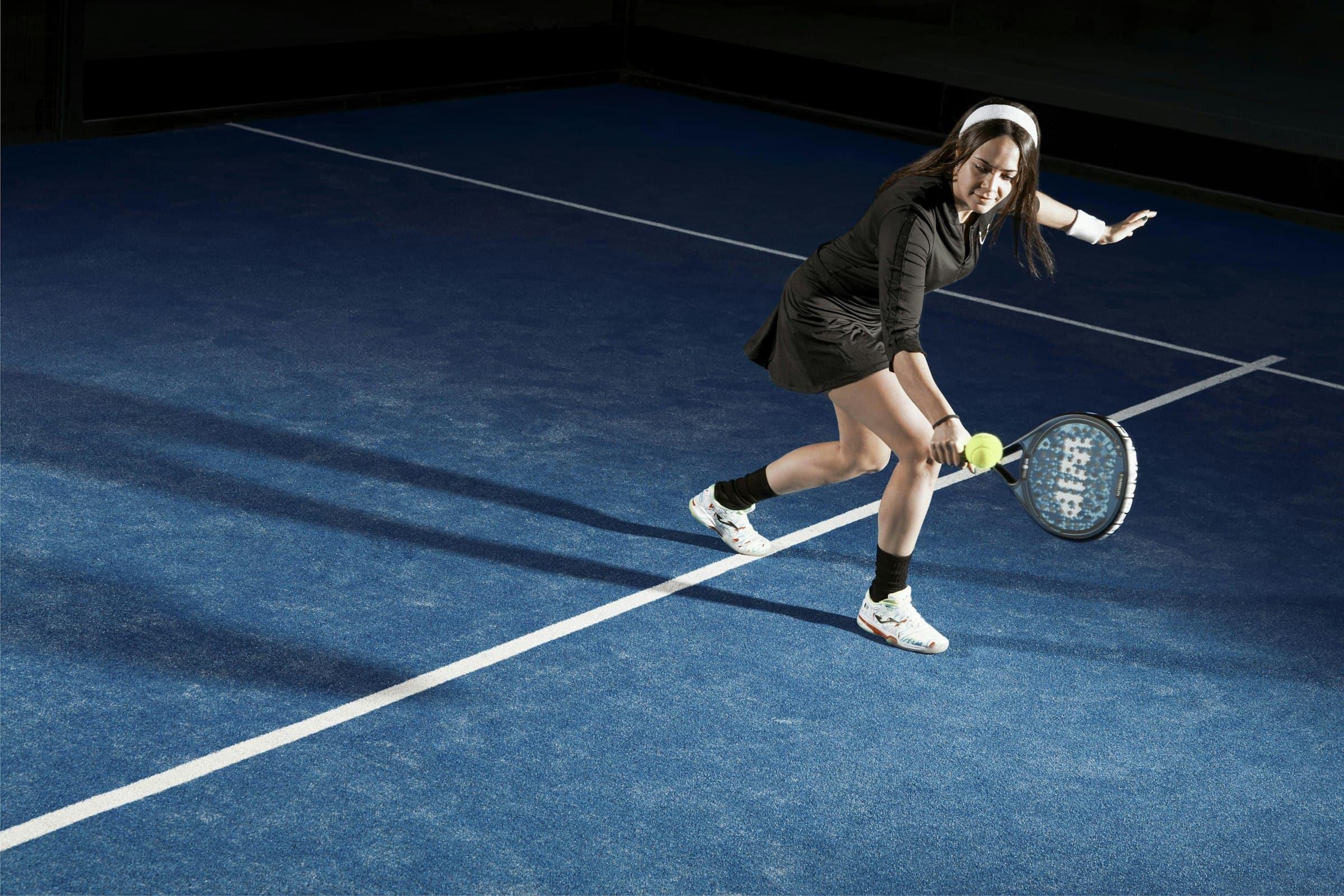 A player lunging for a low forehand on a blue court